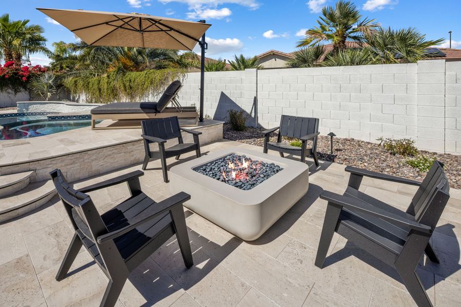 Fire pit with lounge chairs beside the pool and umbrella
