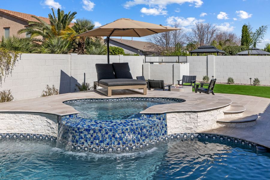 Raised spa with blue mosaic tile and a shaded daybed