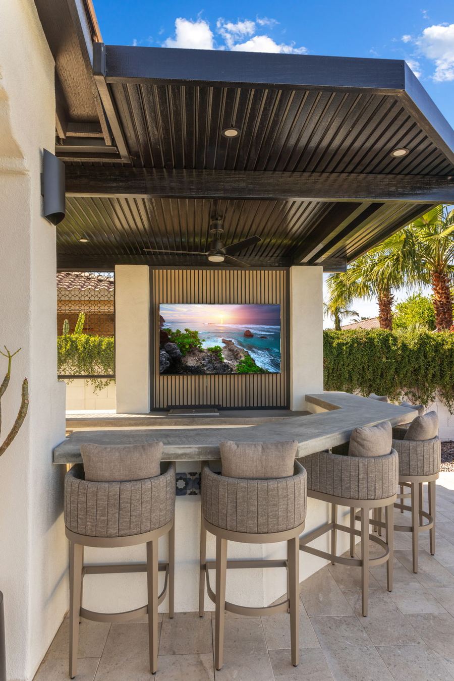 Covered outdoor bar with stools and wall-mounted TV