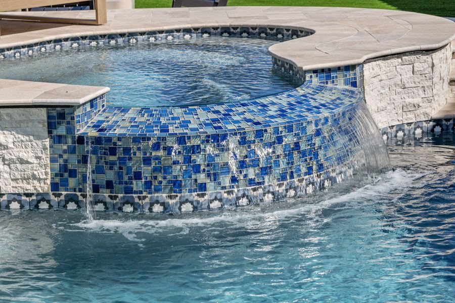 Blue mosaic tile spa spilling into the pool