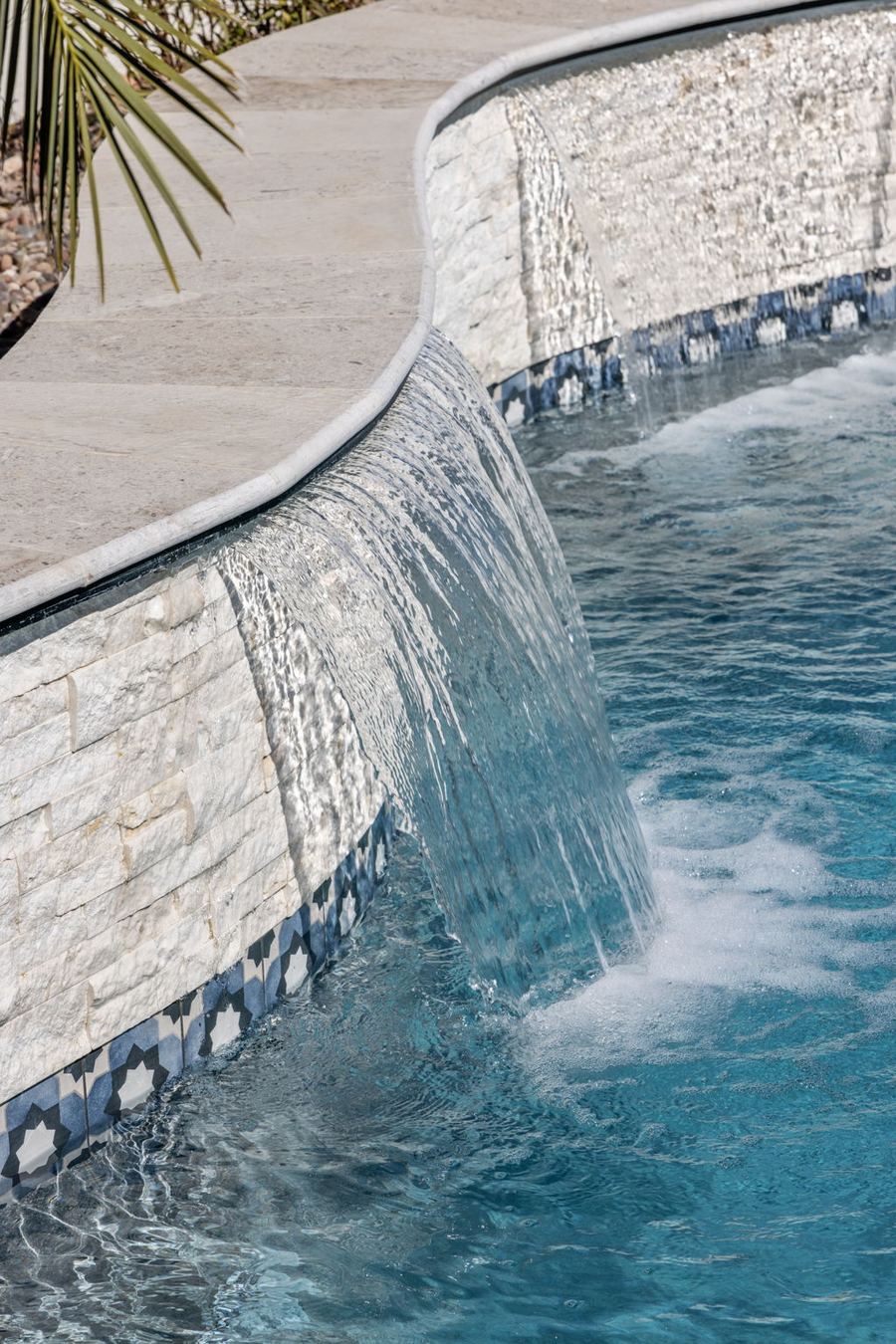 Sheer water feature pouring from a stacked stone wall