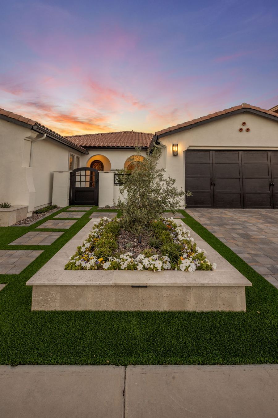 Raised front planter with olive tree and white flowers at dusk
